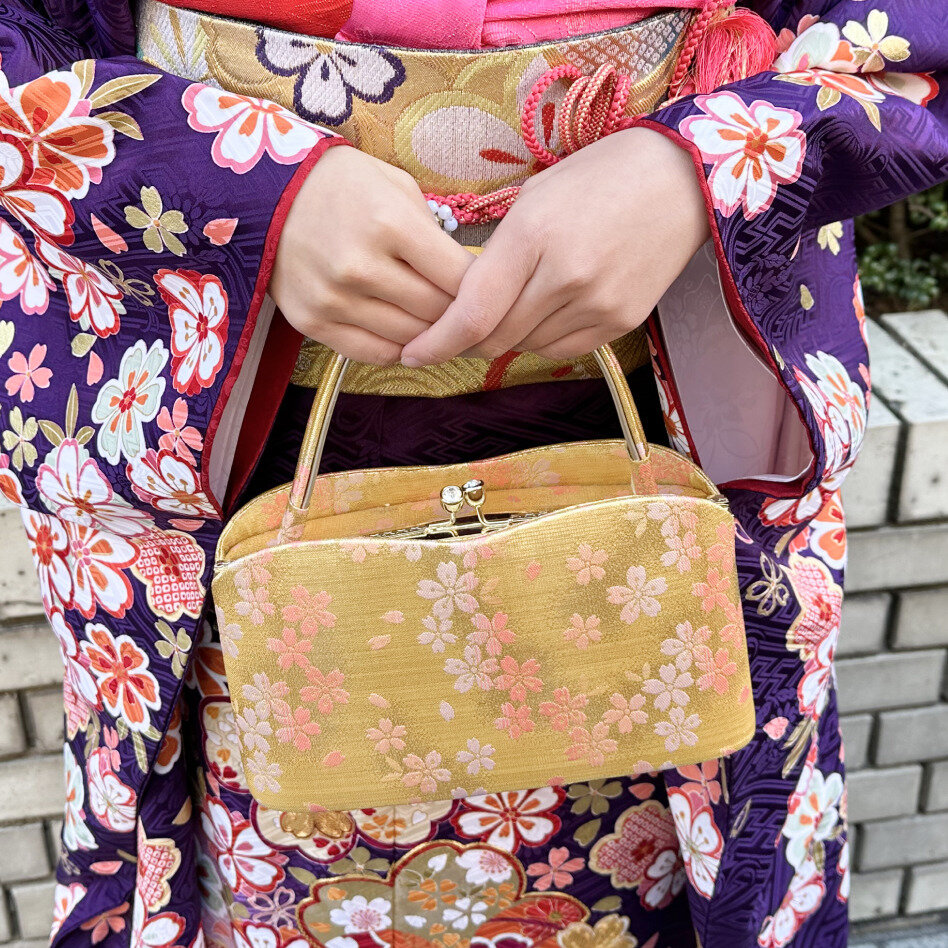目を引くゴールド系の生地に桜柄をあしらったバッグは、帯の色と合わせてコーデにまとまりを出して。